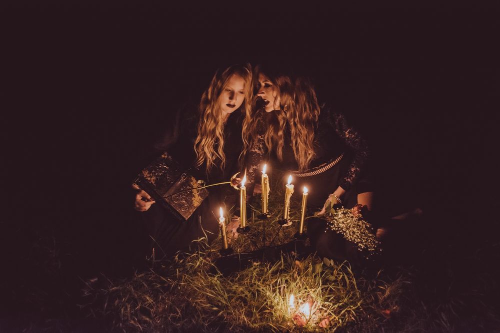 Dark moody scene with candlelight and figures in gothic attire.
