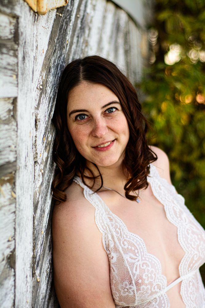 An intimate portrait with soft lighting against weathered white wood siding.