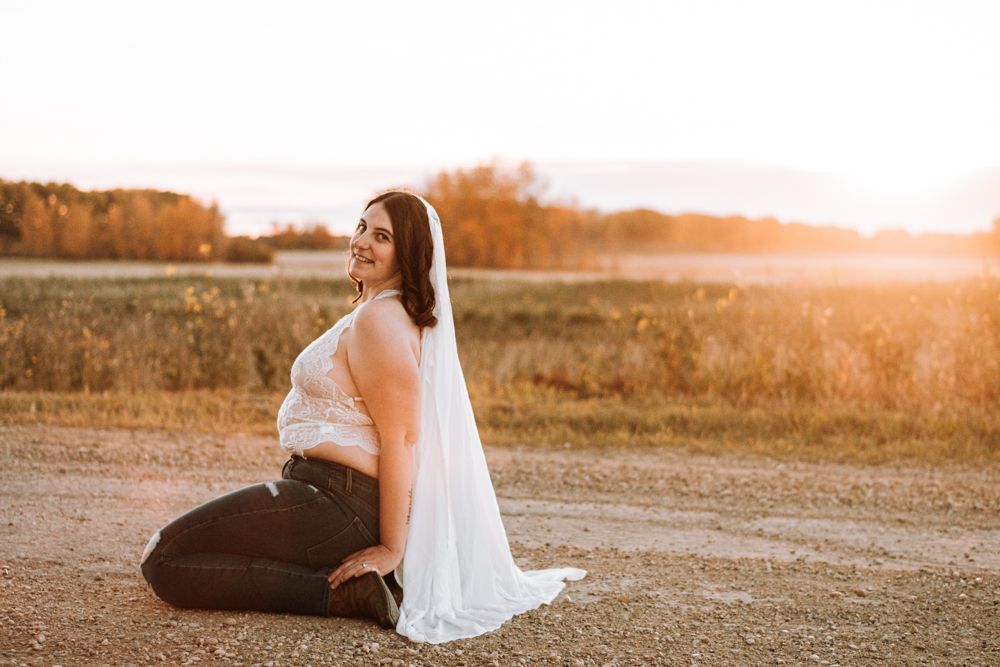 Figure in white top and dark jeans poses on ground during golden hour.