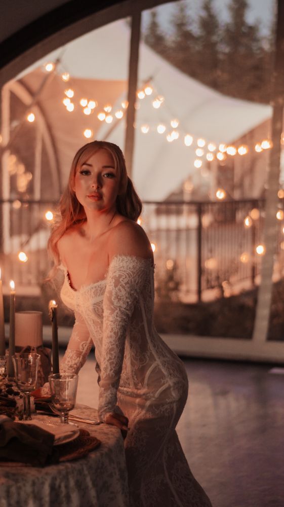Ethereal wedding scene with soft lighting and lace dress against bokeh fairy lights.