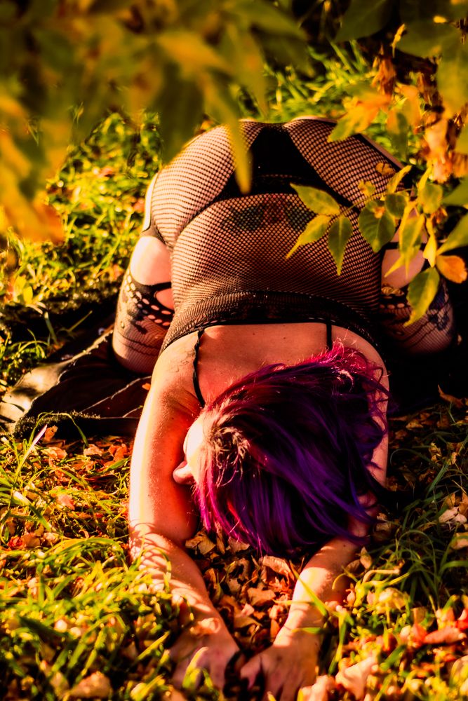 Artistic overhead view of boudoir shoot with purple hair against autumn ground.