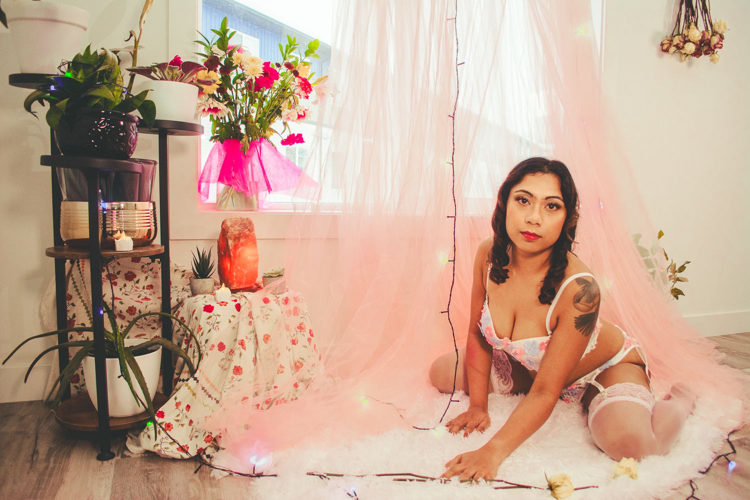 Boudoir scene with pink curtains, potted plants and romantic lighting setup.