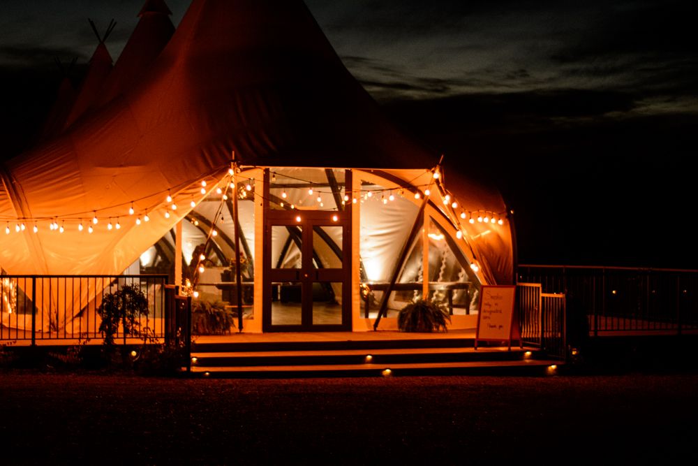 Illuminated outdoor tent venue glowing warmly against dark night sky.