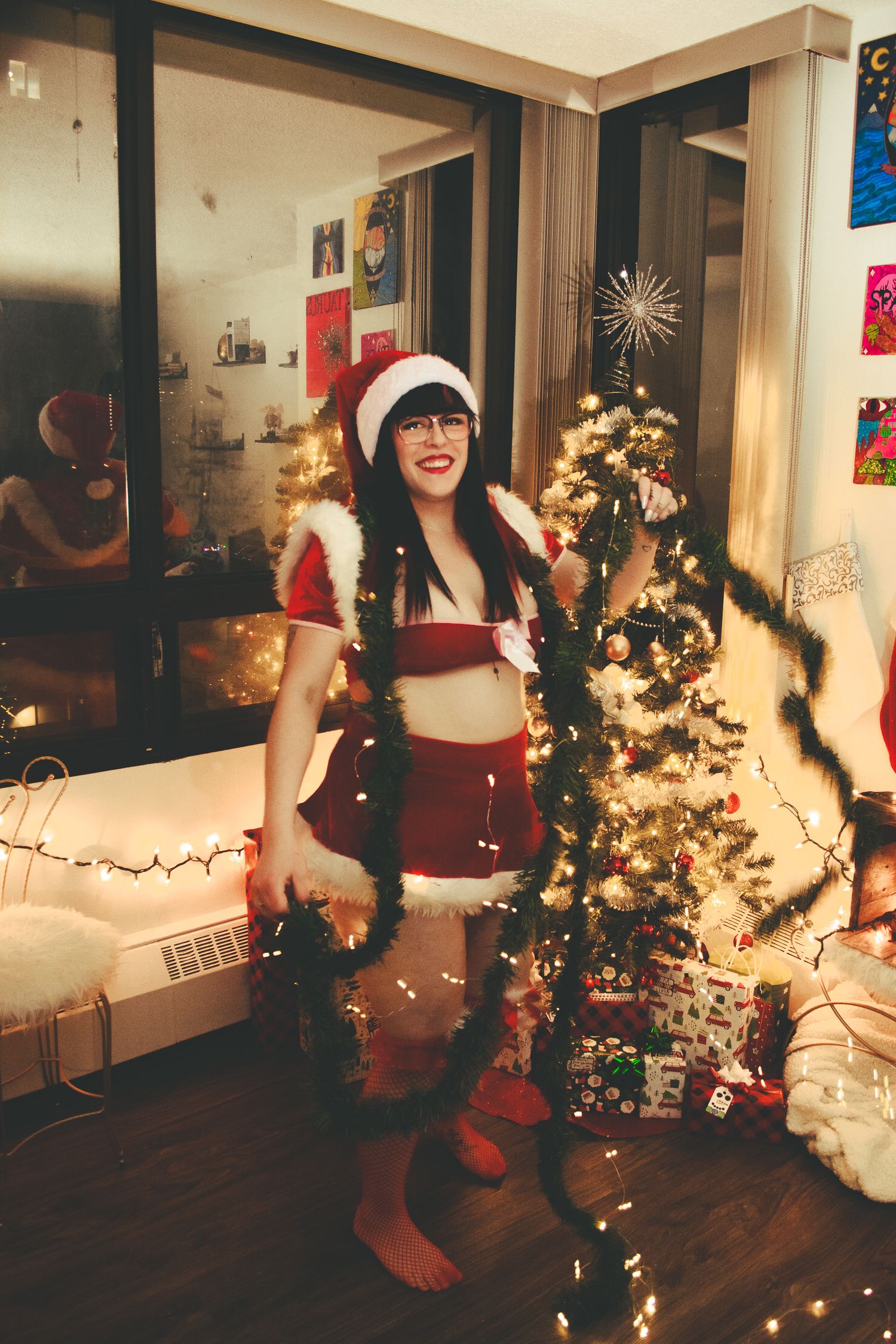 A full-length holiday portrait with Christmas garland and Santa outfit in a decorated room.