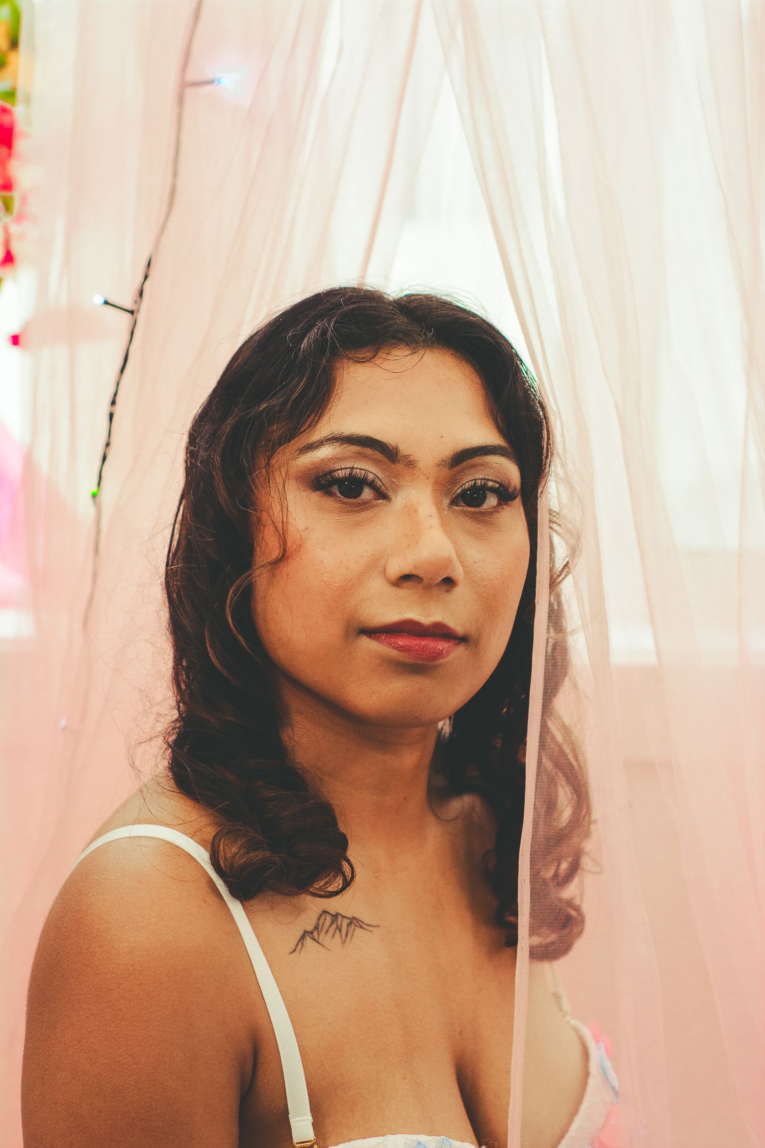Glamour portrait with soft lighting and pink curtain backdrop.