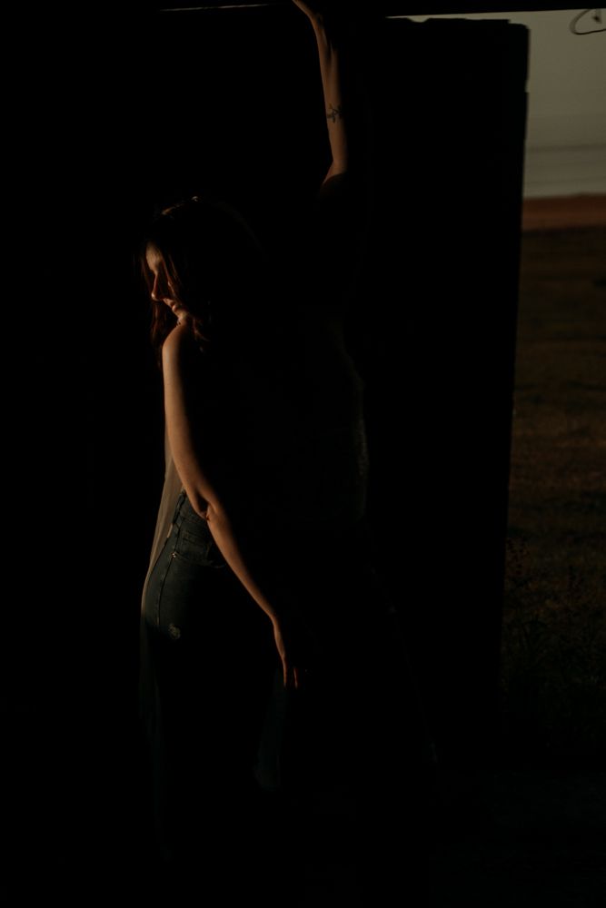 Artistic low-light portrait with figure emerging from shadows.