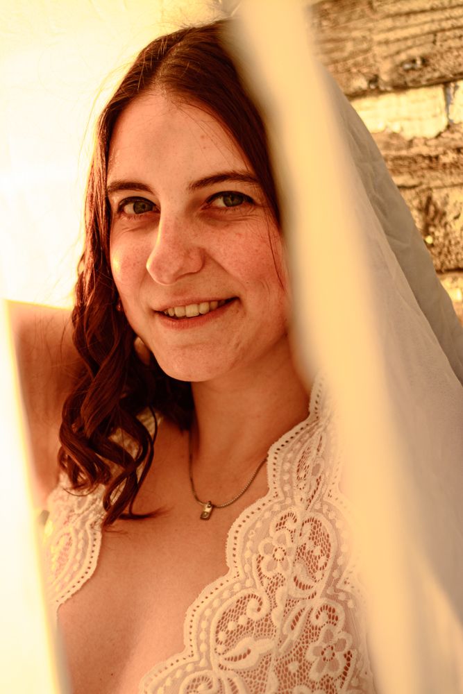 Artistic portrait through veil with rustic barn background during sunset.