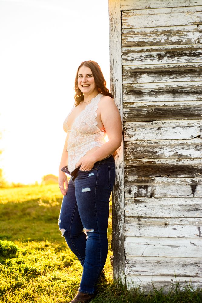 Casual outdoor portrait against rustic white barn wall during sunset.