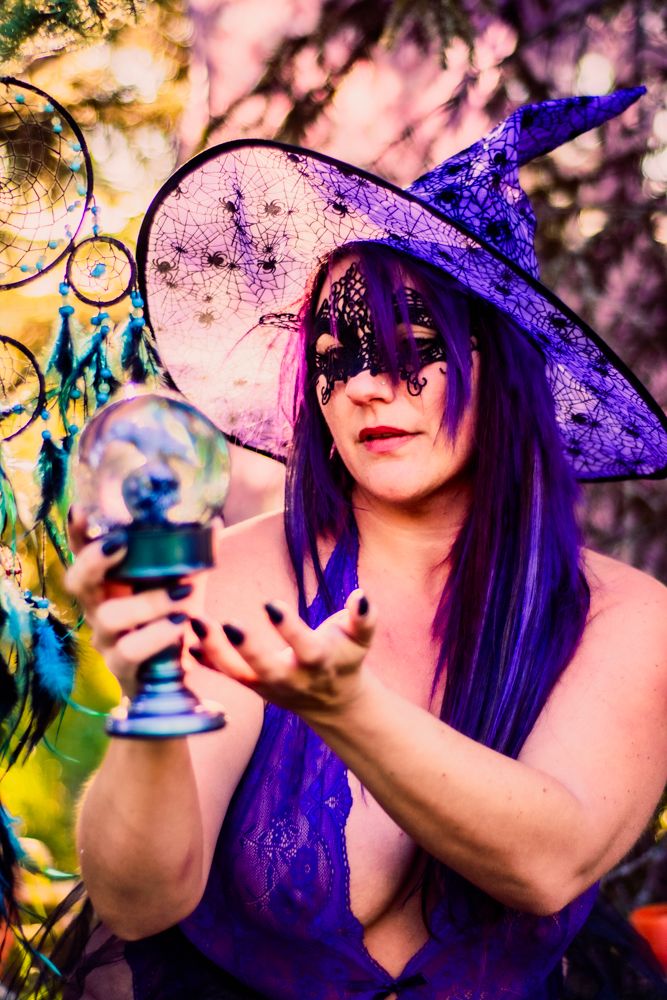Mystical Halloween scene with crystal ball, purple witch hat, and dreamcatchers in golden light.