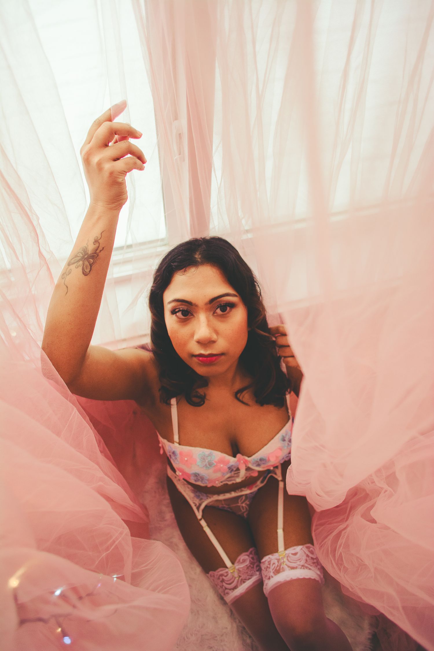 Artistic boudoir shot with flowing pink tulle and twinkling lights.