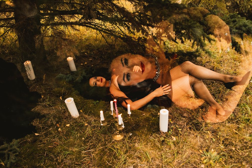 Artistic outdoor portrait on forest floor with scattered white candles.