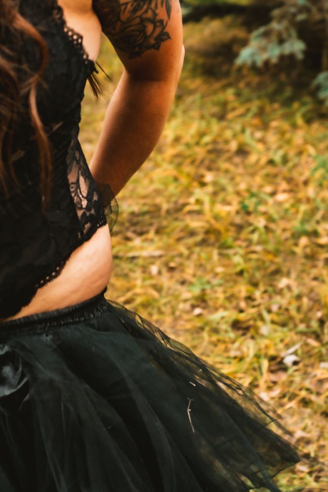 Close-up detail of black lace and tulle dress against autumn grass.