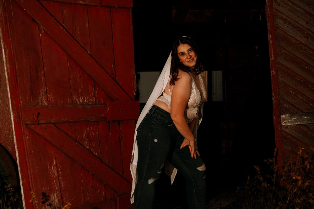 A rustic fashion photoshoot by a red barn door featuring dramatic lighting and contemporary style.
