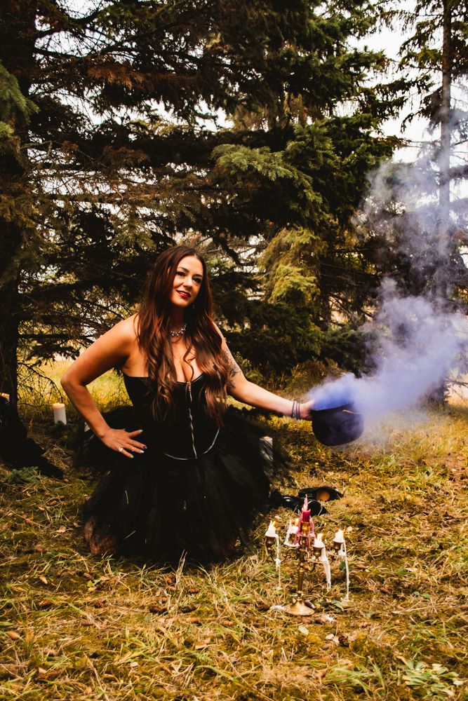 Whimsical forest photoshoot featuring black dress and blue smoke effects.