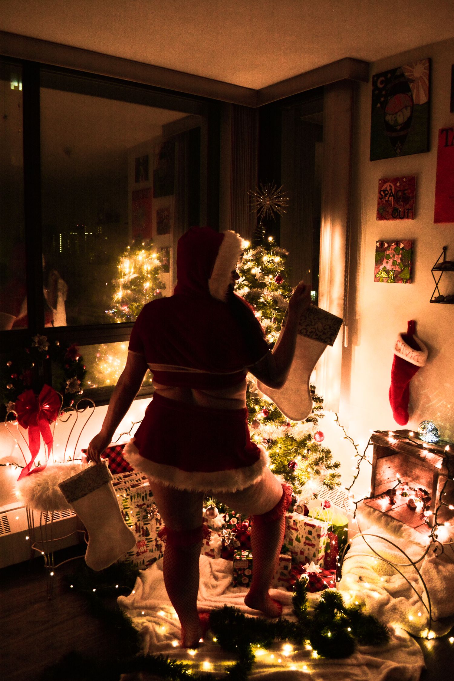 A silhouette against a decorated Christmas tree and stockings in a cozy holiday setting.