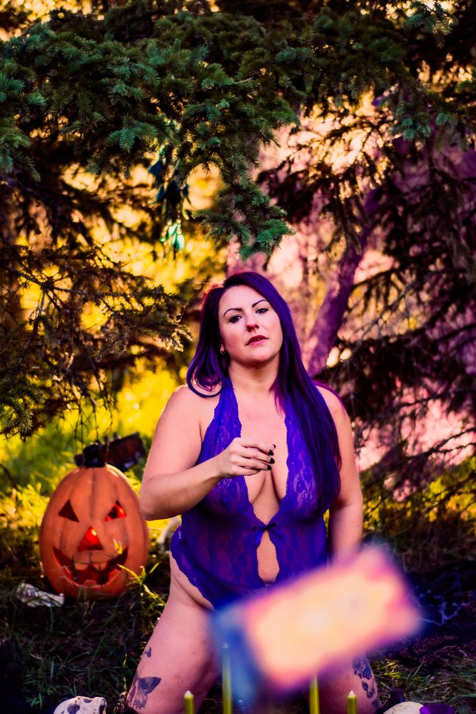 Artistic Halloween portrait with jack-o'-lantern and mystical purple lighting effects.