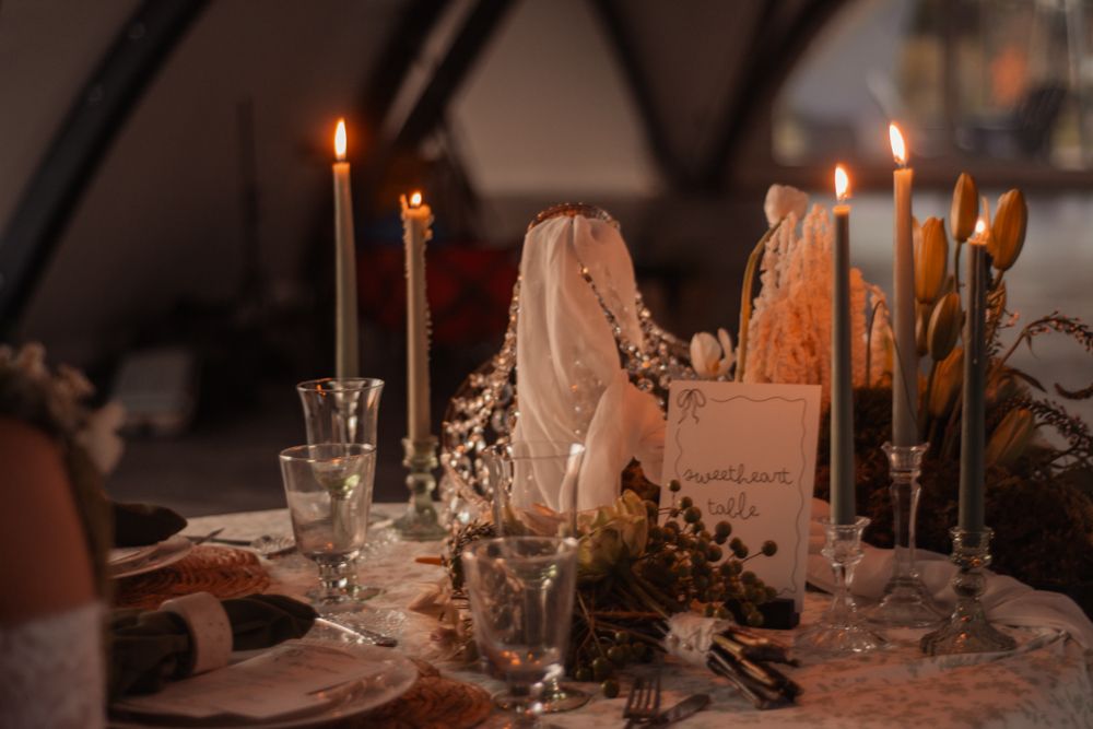 Elegant wedding table setting with lit candles, glassware and romantic decor.