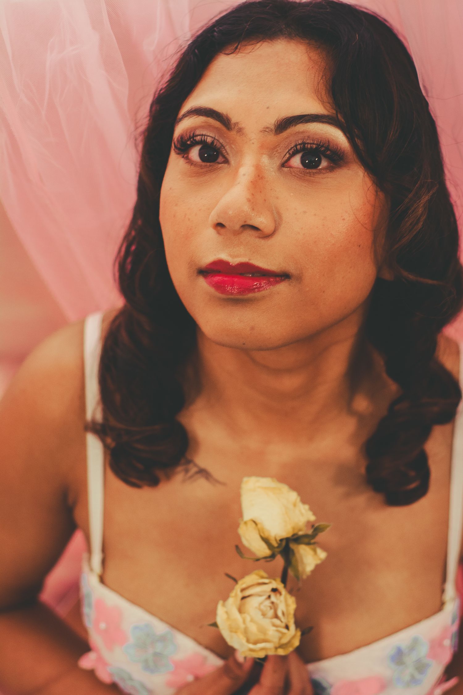 Glamour portrait featuring red lipstick and cream roses against pink background.