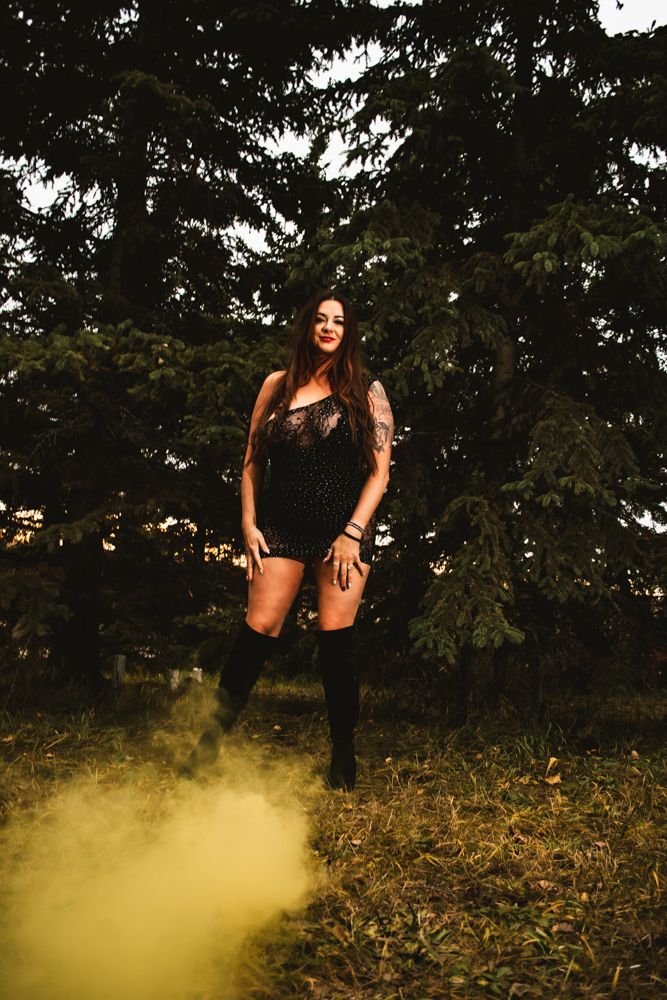 Fashion portrait with yellow smoke effects in forest setting.