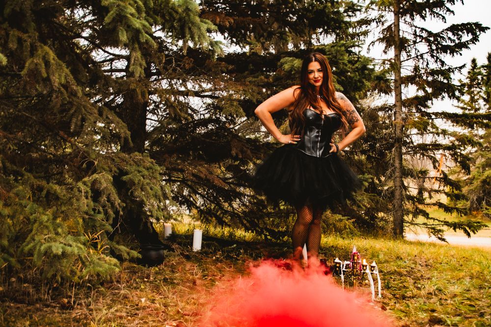 Dramatic outdoor portrait with figure in black tulle dress and red smoke effects.