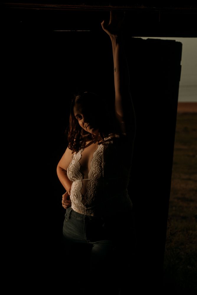 Dramatic side-lit portrait showing lace detail against rustic wooden background.
