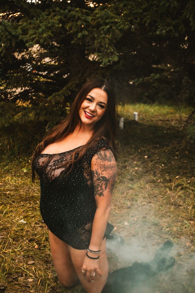 Portrait showcasing sparkly black attire and tattoo art in natural outdoor lighting.