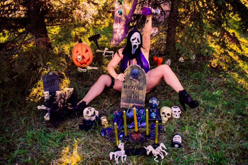 Halloween cemetery scene with glowing candles, decorative skulls and pumpkins in outdoor setting.