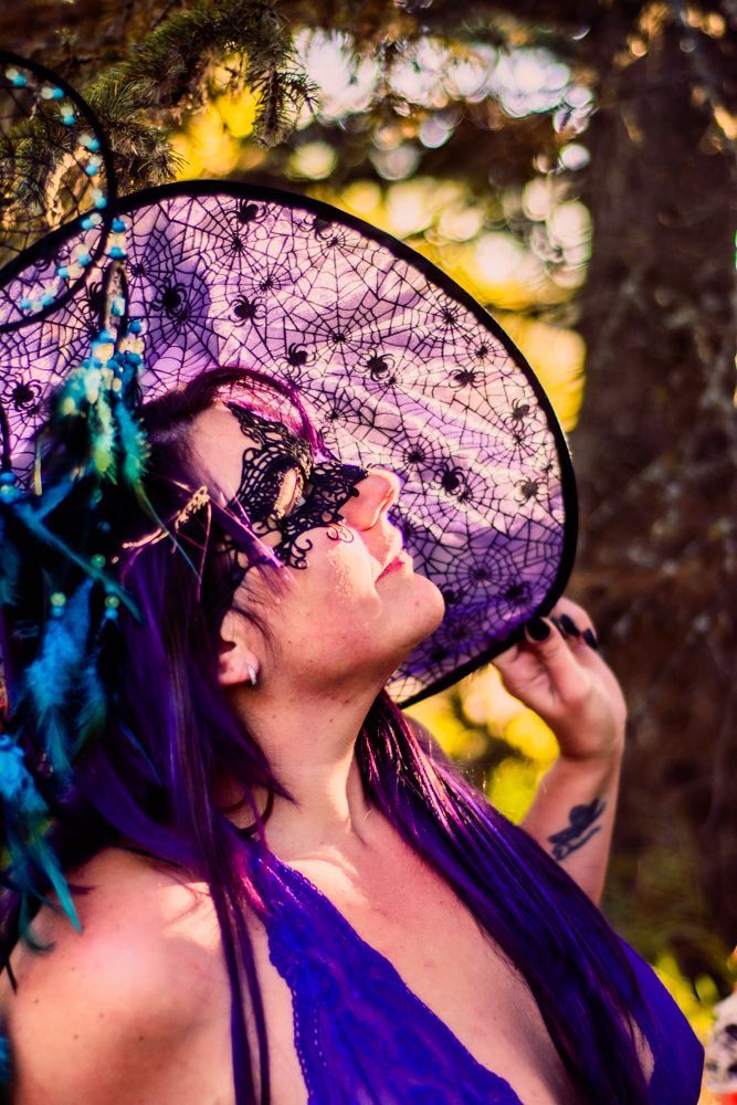 Purple lace hat with spider web design silhouetted against golden sunset through trees.