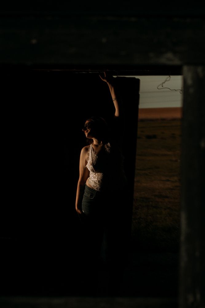Backlit silhouette framed in rustic doorway at sunset.