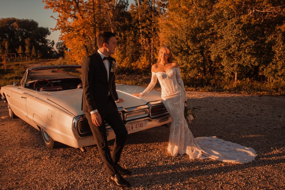 Classic white convertible car on autumn day beside orange fall foliage.