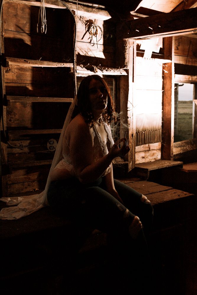 Atmospheric low-light portrait in historic barn setting with vintage wooden fixtures.