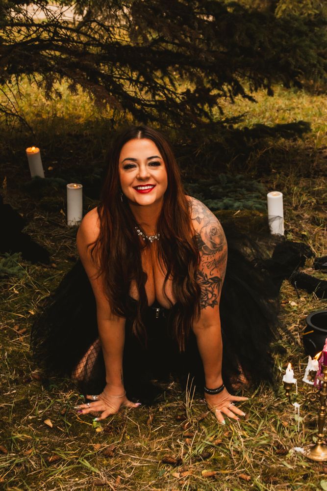 Artistic forest photoshoot with candles and gothic attire on forest floor.