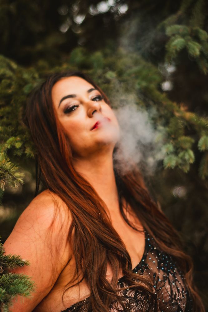 Artistic portrait with smoke effects and lace attire against natural forest backdrop.