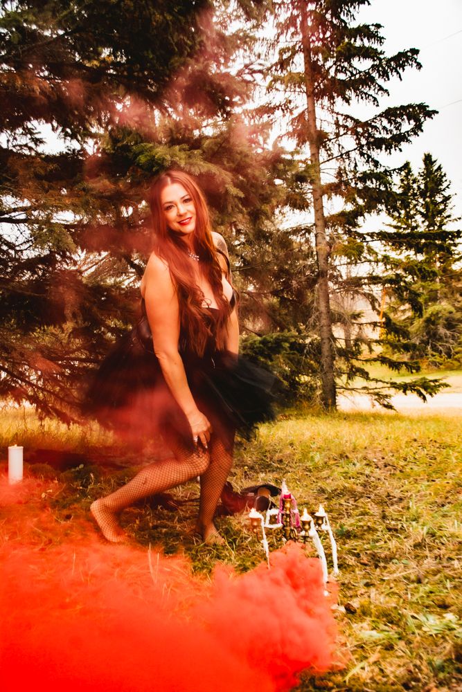 A mystical forest photoshoot features red smoke effects and gothic fashion aesthetics.