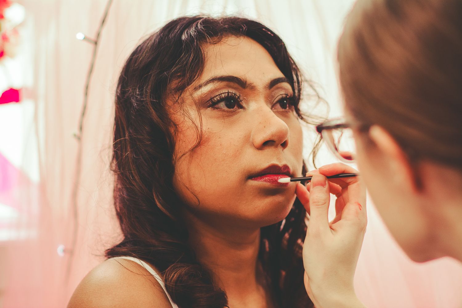 Professional makeup application in progress with pink floral accents.
