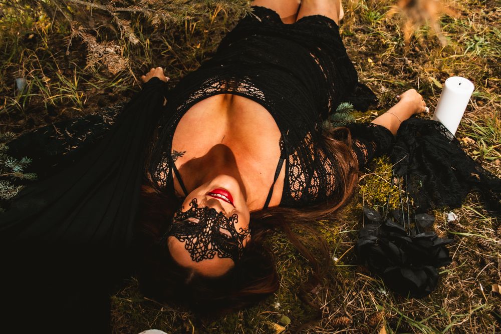 Outdoor portrait with black lace mask and dress surrounded by white pillar candles.