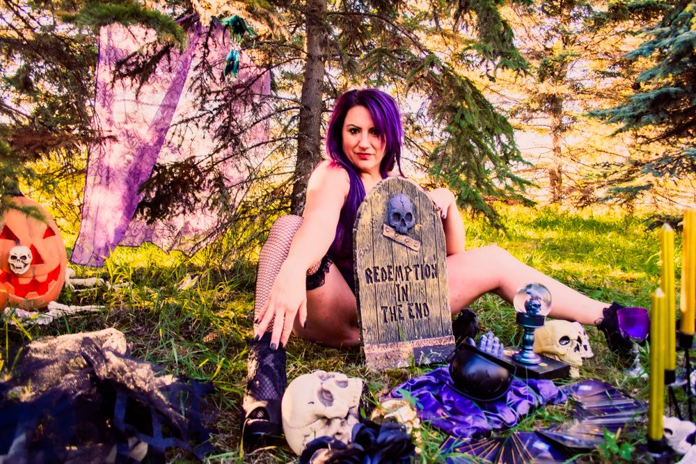 Artistic Halloween scene with purple lighting effects, gothic props and forest background.