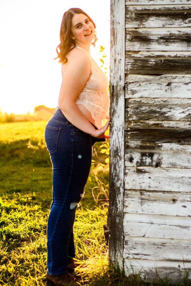 Model posing playfully by rustic barn wall during golden hour photography session.