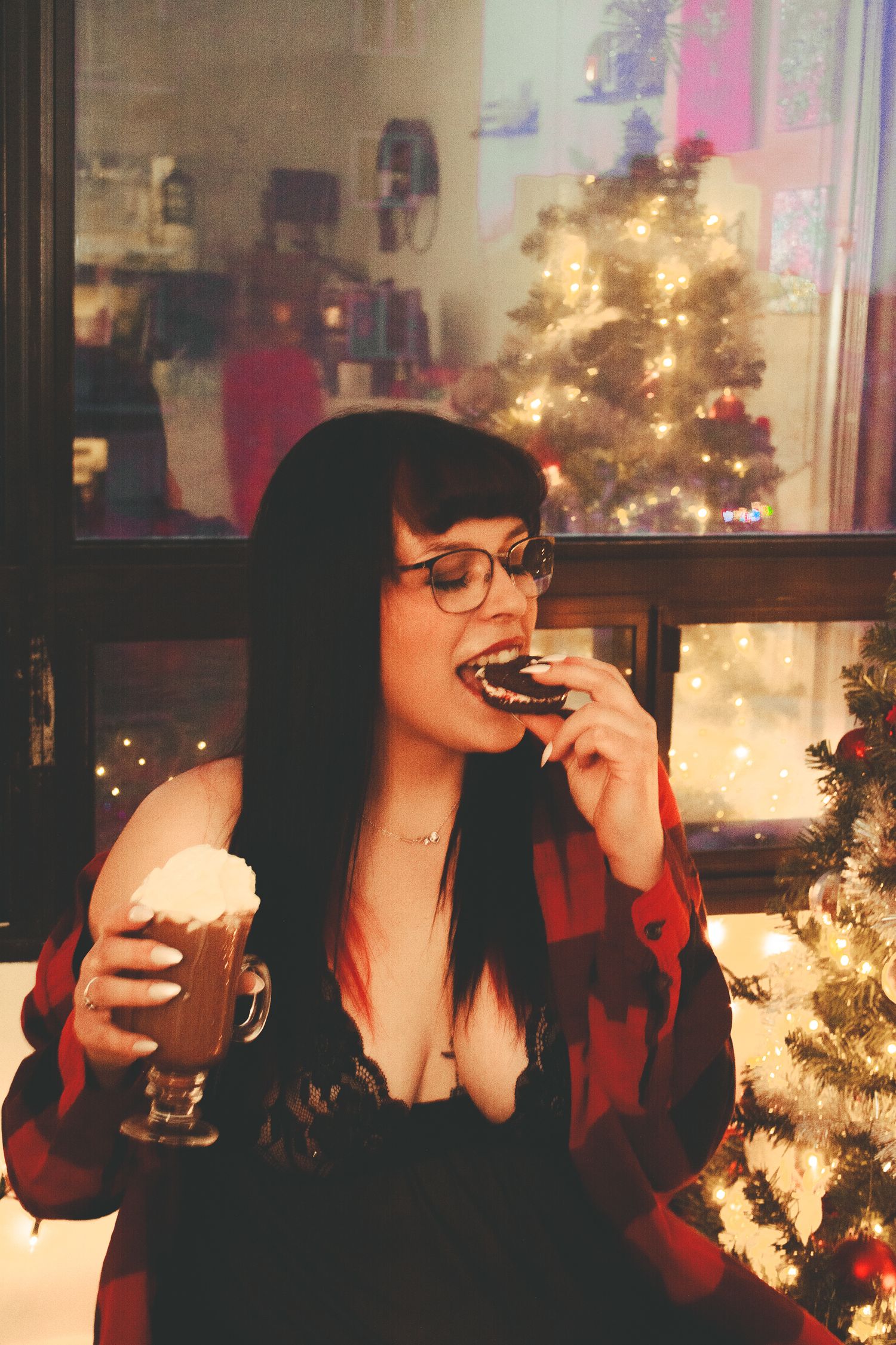 Holiday celebration scene with a beverage and cookie against a lit Christmas tree backdrop.