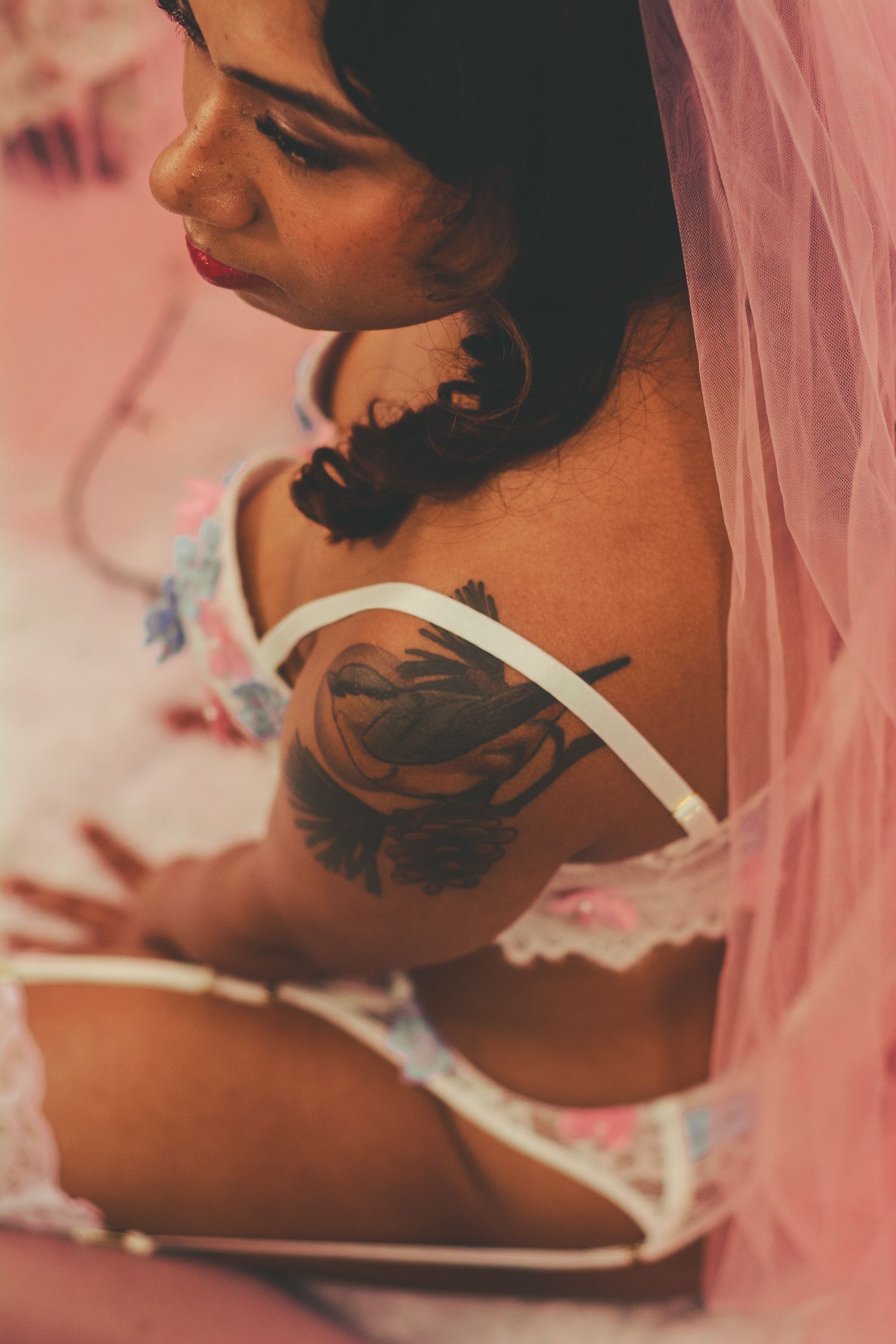 Intimate side profile portrait showcasing artistic tattoo against pink drapery.