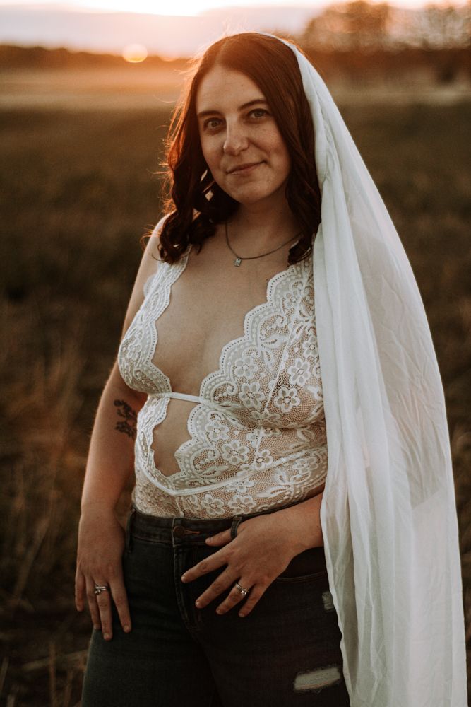 Portrait in warm sunset light featuring white lace top and flowing veil.