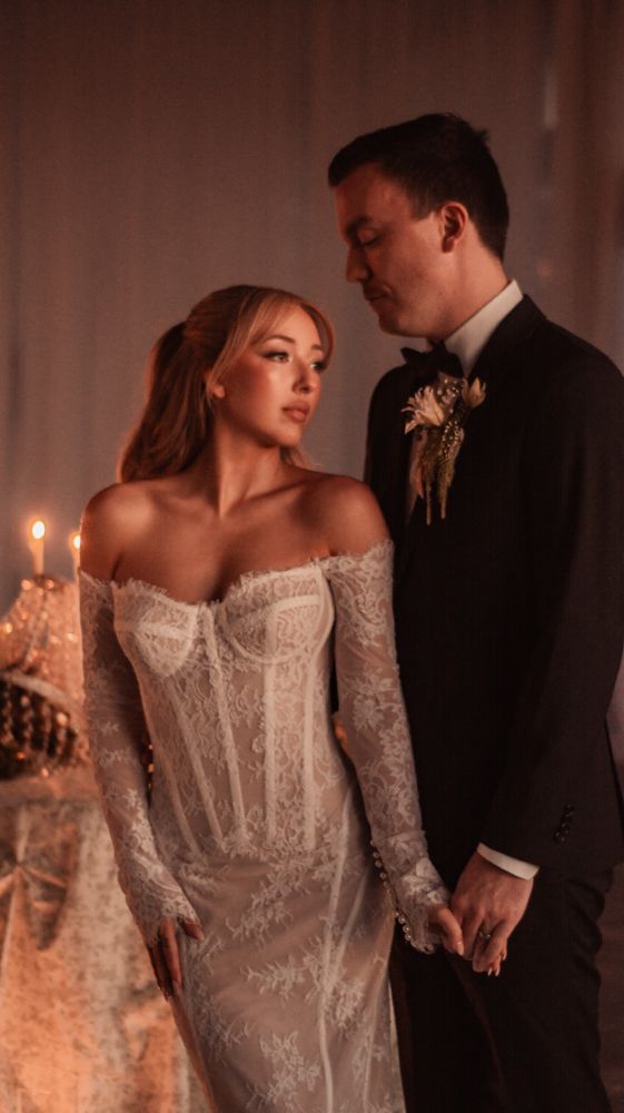 Tender wedding moment captured in warm candlelight with elegant formal attire.