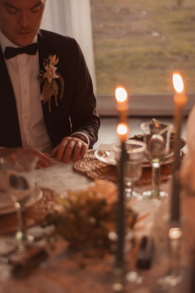 Formal table setting with candles and elegant dinnerware at wedding reception.