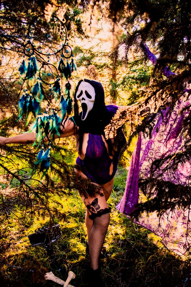 Halloween themed photo with ghost mask and purple accents against sunlit forest background.