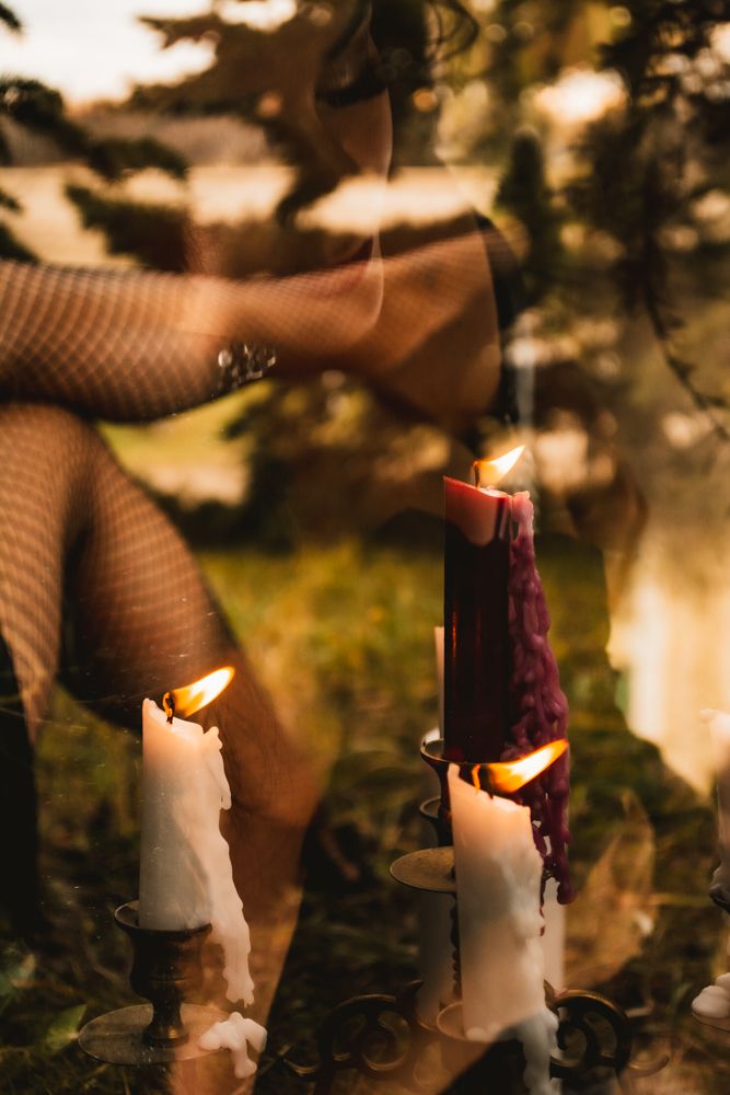 Close-up of lit candles with fishnet stockings in forest setting.