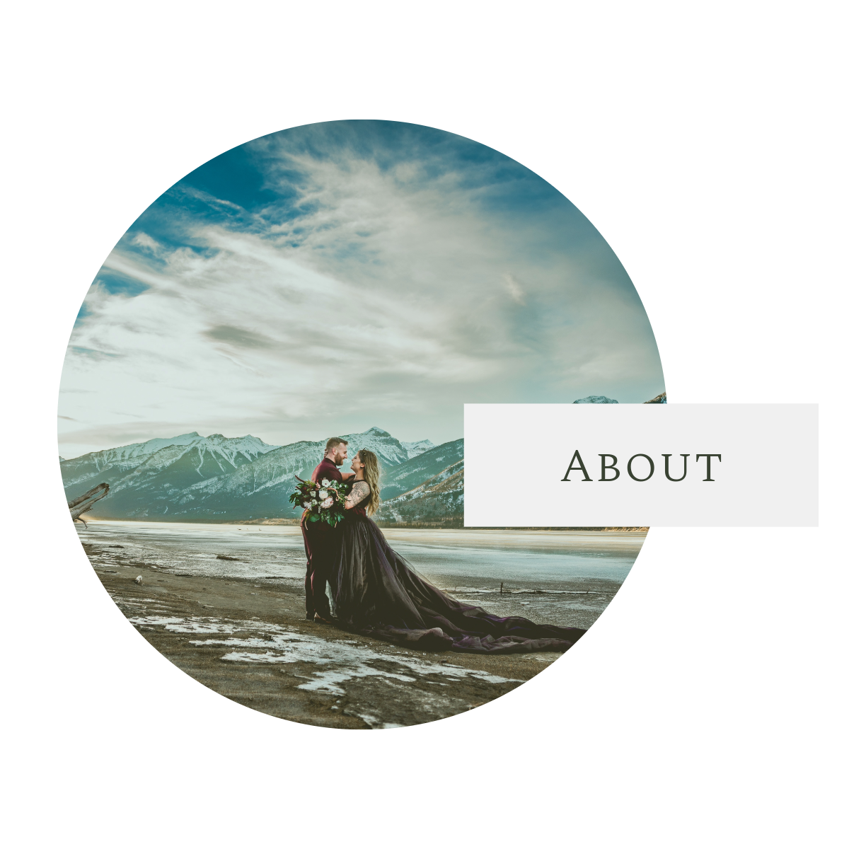A couple in elegant attire stands against a dramatic mountain landscape with moody clouds and snow-capped peaks in view.