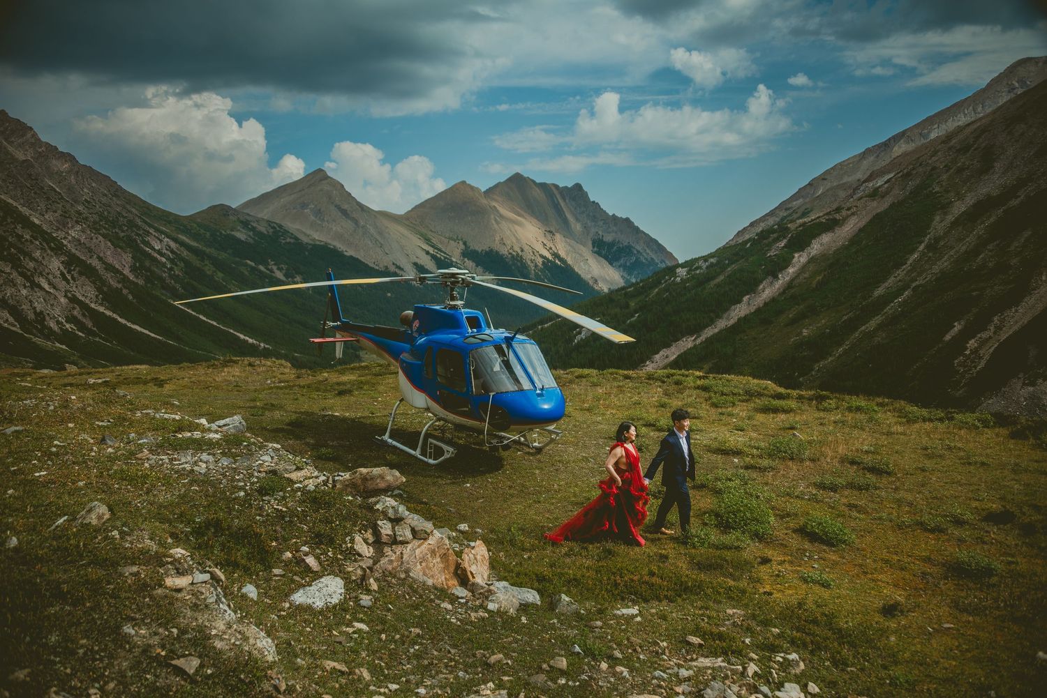 Scenic mountain landscape wedding with helicopter set against dramatic cloudy skies in remote wilderness.