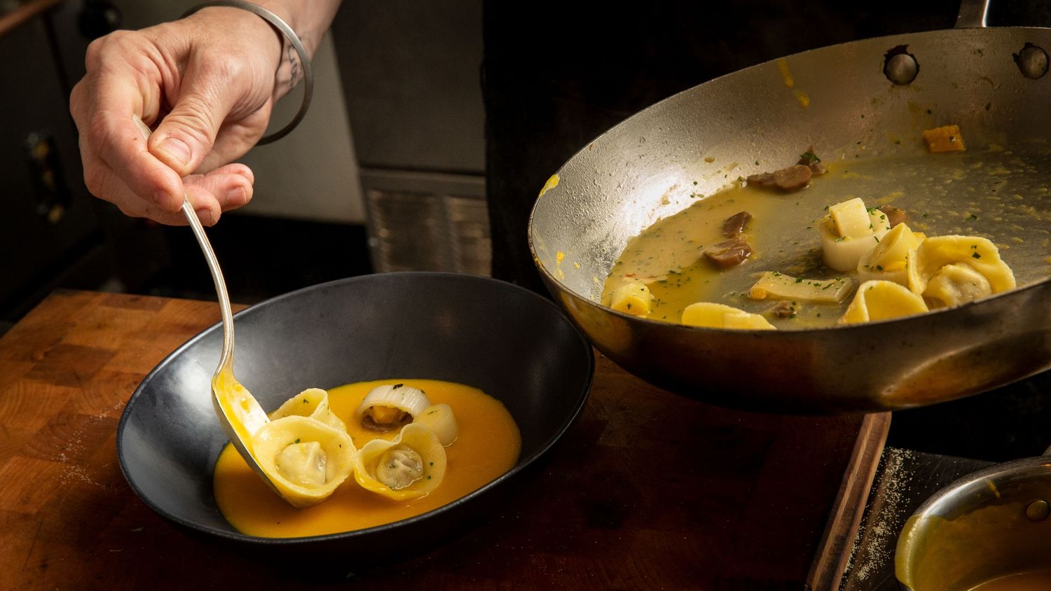 Cooking process of yellow curry or soup dish in metal pans.