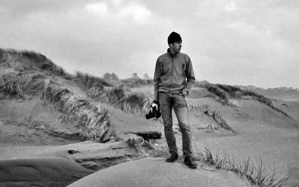 Black and white landscape series showing a person exploring sandy coastal dunes.