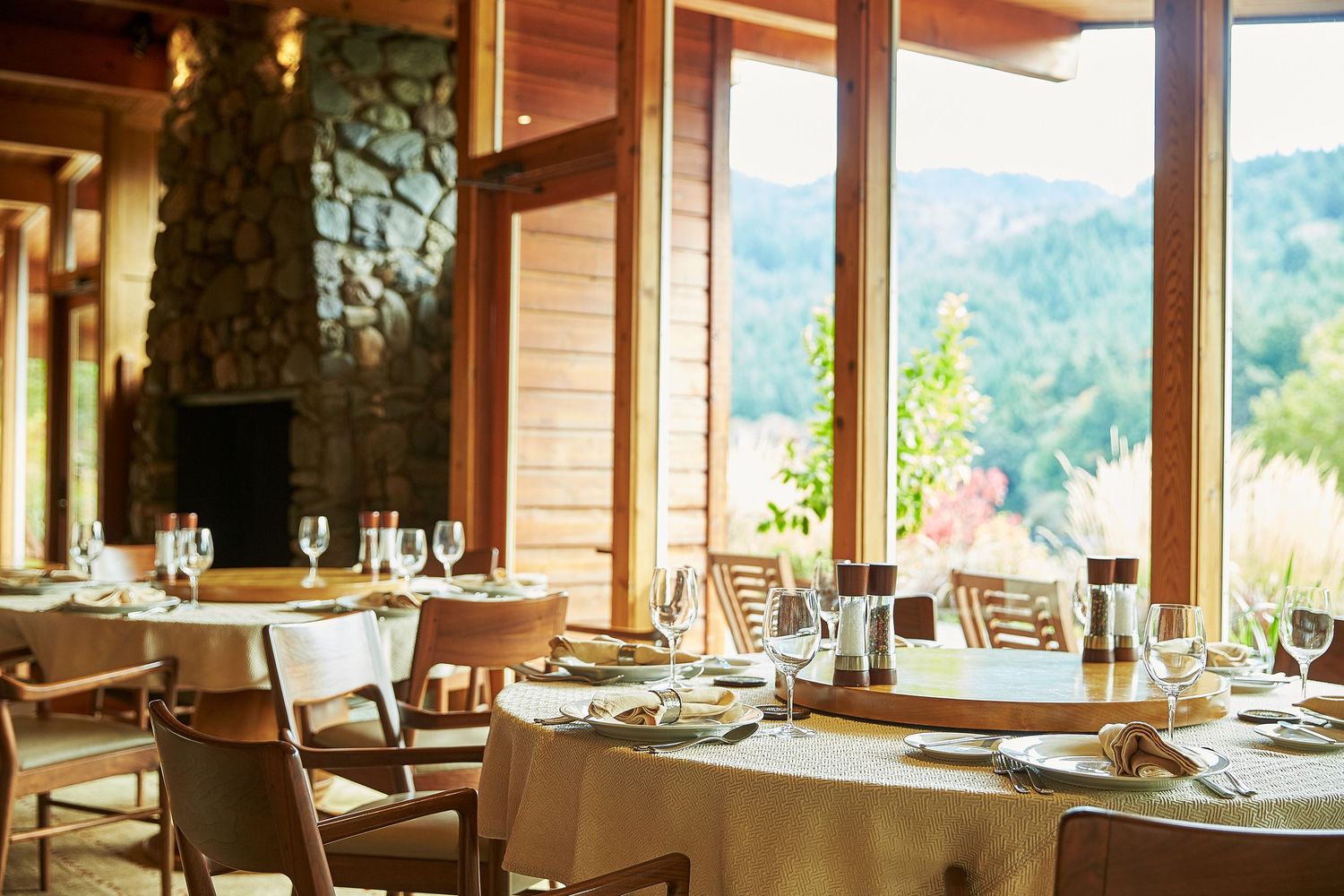Restaurant dining room with large windows offering panoramic mountain and water views.